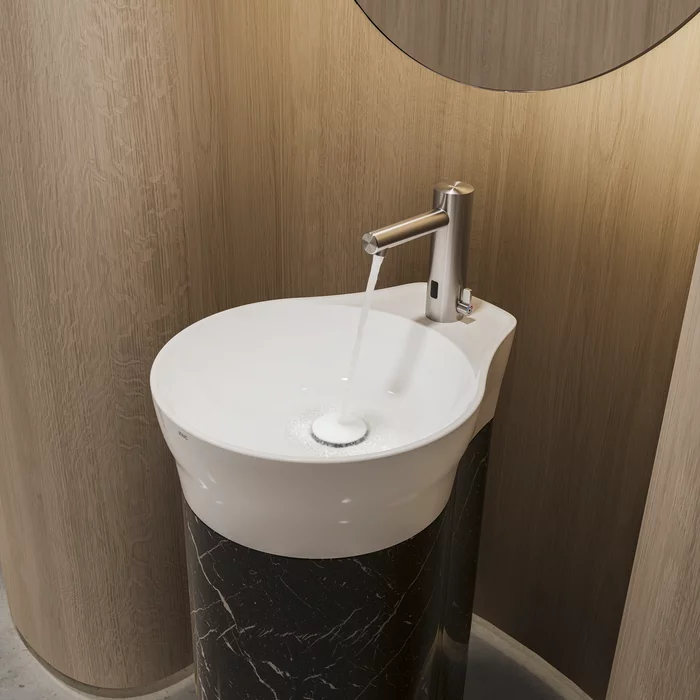 Witte wastafel met zilveren kraan en spiegel erachter.