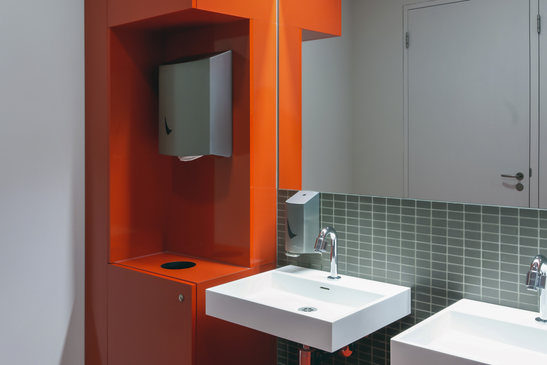 Wastafels met kranen en een rode afvalhoek van Wings aan de linkerkant.