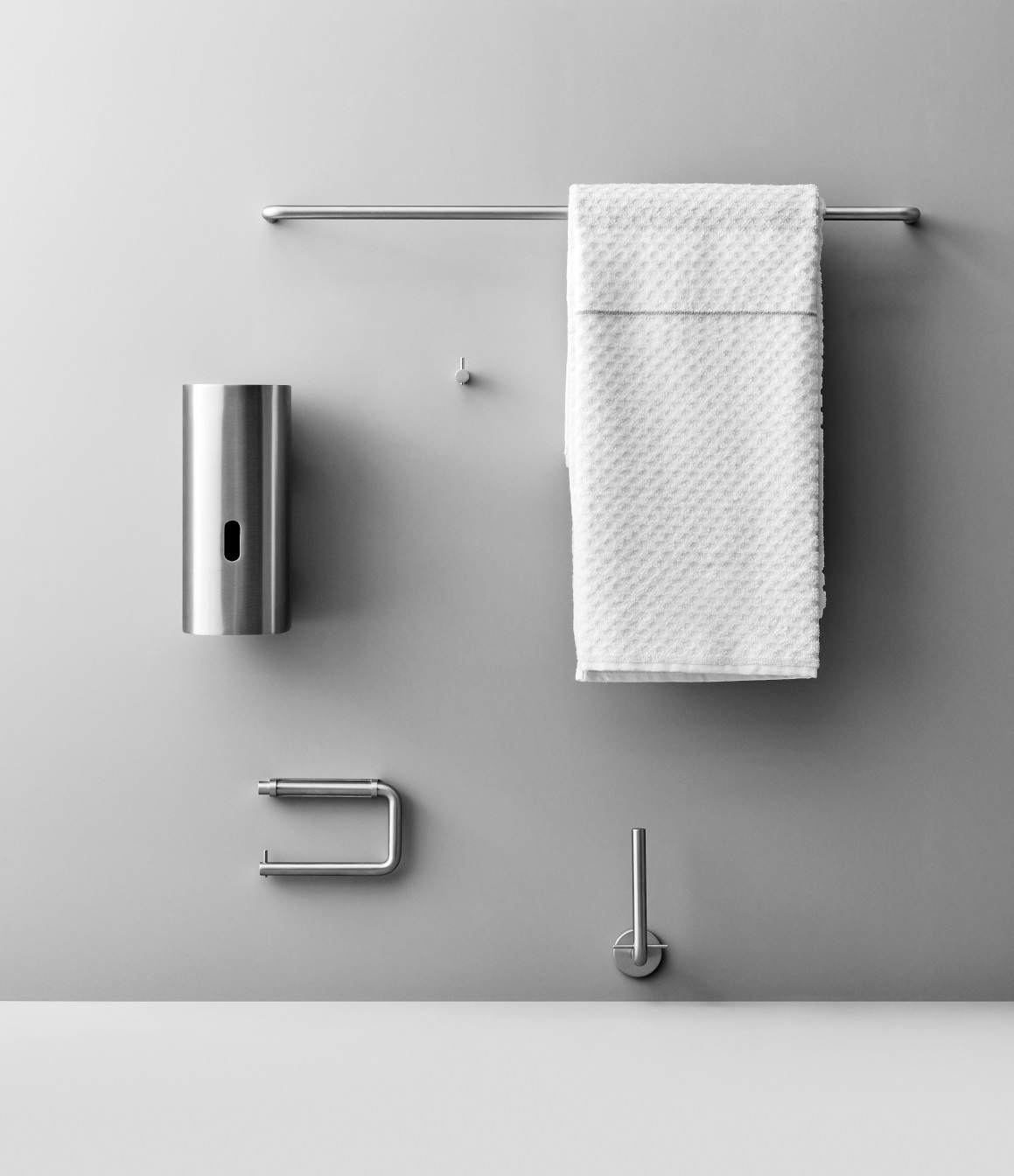 Grijze accessoires in een sanitaire ruimte, inclusief handdoekrek en dispenser.